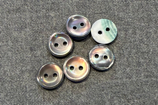 Set of pearly grey buttons on a gray fabric background