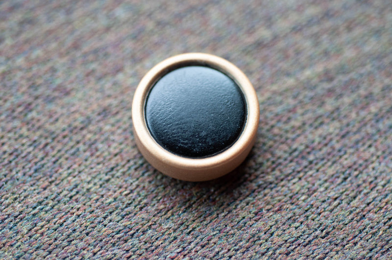 Round black object with a gold rim on a textured surface