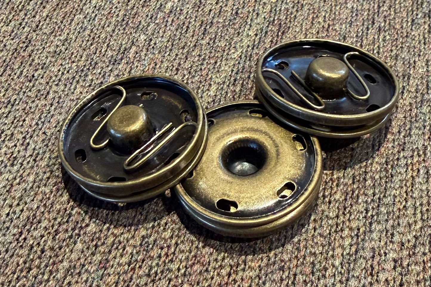 Three metallic snaps on a textured fabric surface
